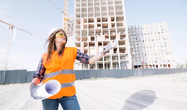 Arquitecta en la Administración pública con planos en un entorno urbano en transformación.