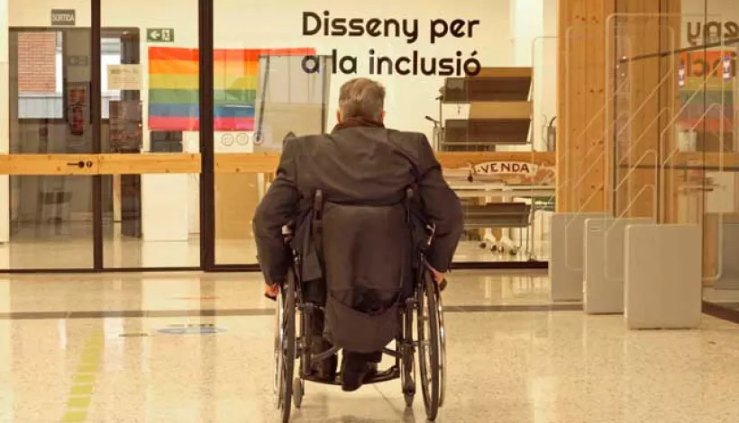 Un hombre en silla de ruedas entrando por la puerta de la biblioteca