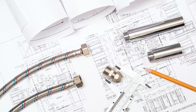 Componentes hidráulicos y herramientas de medición sobre planos arquitectónicos de un edificio residencial