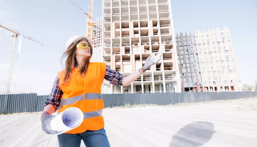 Arquitecta a l'Administració pública amb plànols en un entorn urbà en transformació.