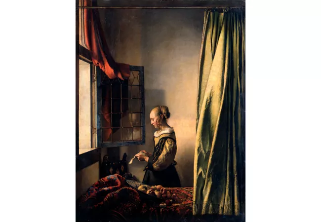 Mujer leyendo una carta junto a la ventana