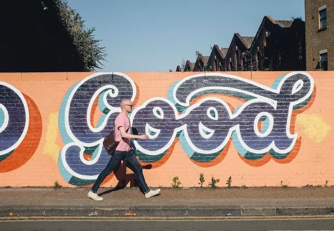 Joven pasando delante de un grafiti que pone Good