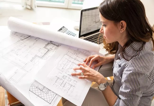 Arquitecta dibujando planos junto a un ordenador