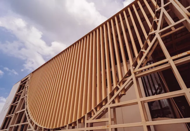 Estructura arquitectónica con lamas de madera en fachada curva, ejemplo de construcción sostenible con madera