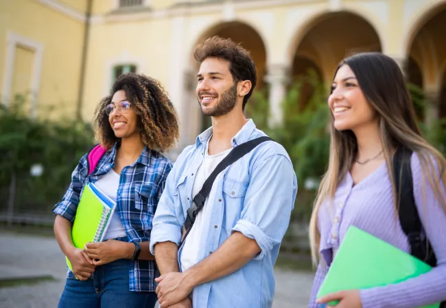 Tres estudiants d'arquitectura caminen pel campus universitari