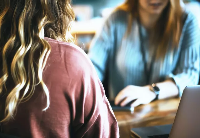 Dos mujeres trabajando juntas con un portátil sobre una mesa, en actitud de coordinación.